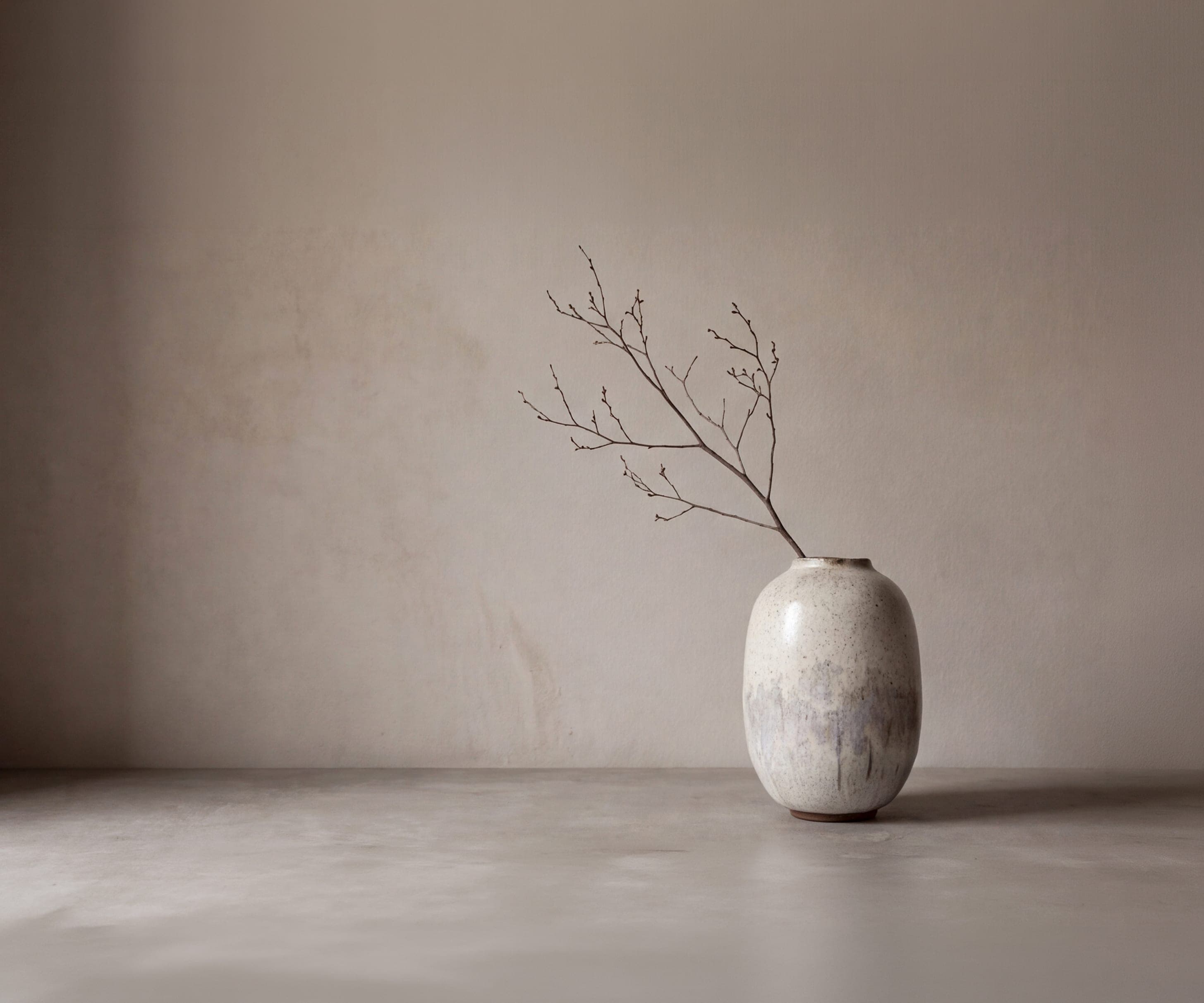 Handmade ceramic vase with a bare branch in a quiet, spacious room
